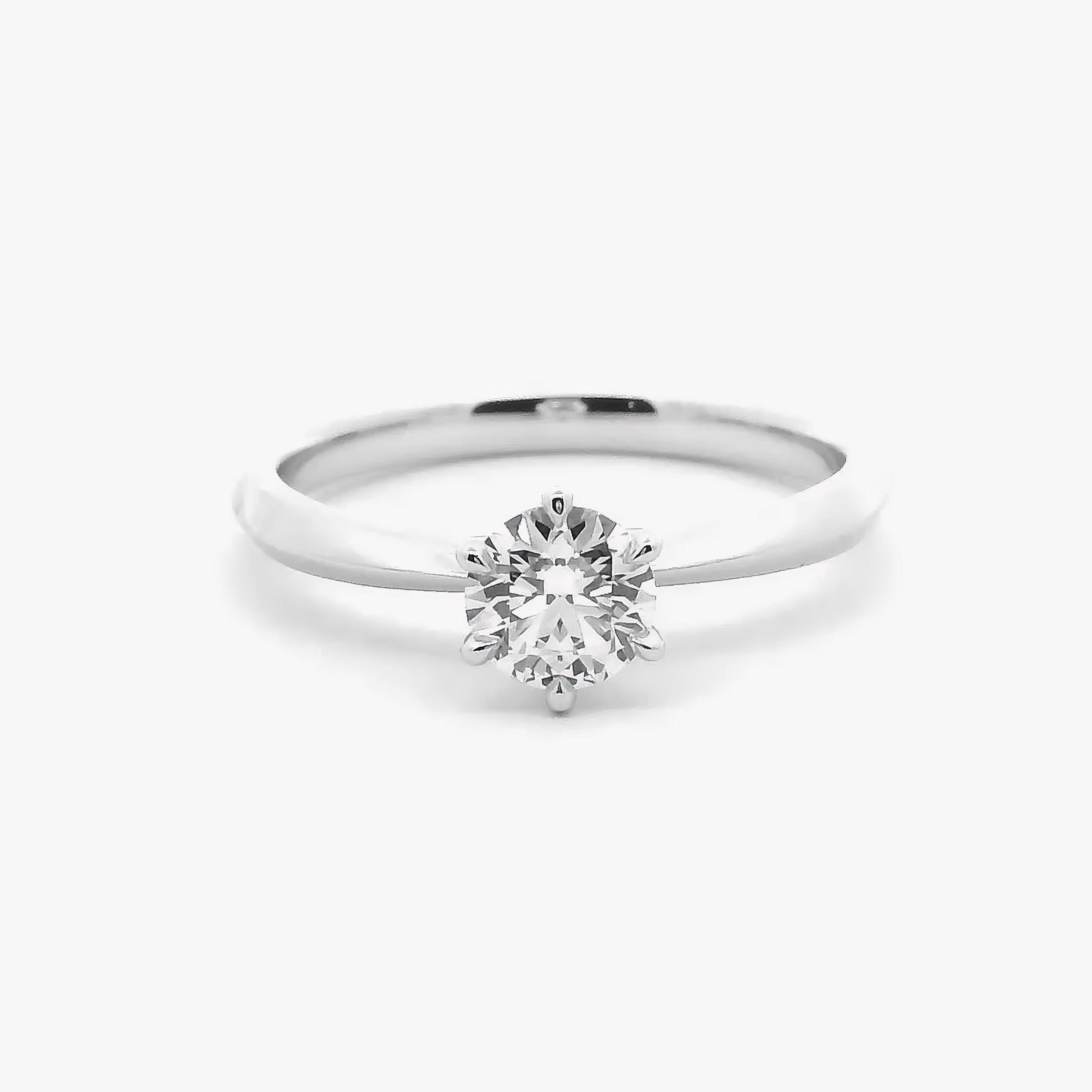 A six-prong round diamond solitaire engagement ring in polished 18K white gold — Diamond Ateliers.