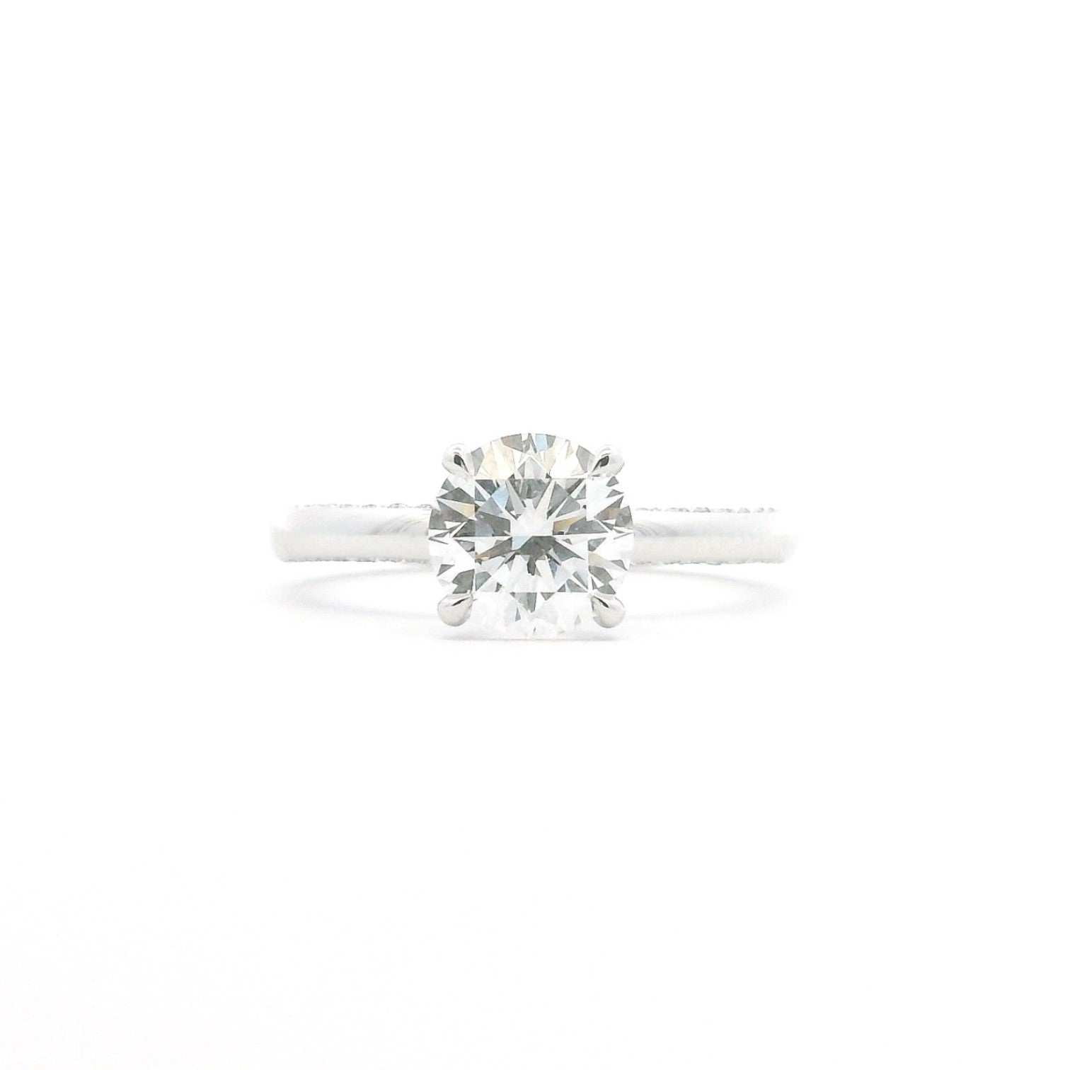 A four-prong round diamond solitaire engagement ring in polished 18K white gold — Diamond Ateliers.