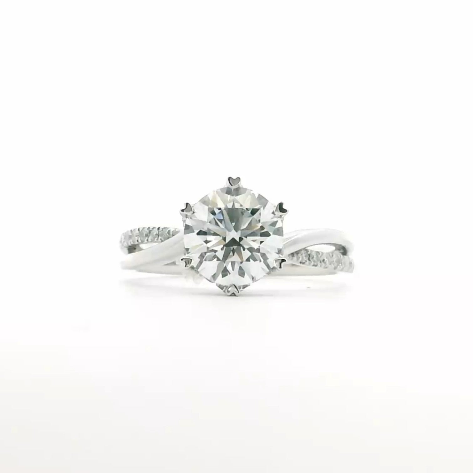 A twist-band solitaire engagement ring with an open arc and 6 heart prongs in polished 18K white gold — Diamond Ateliers.