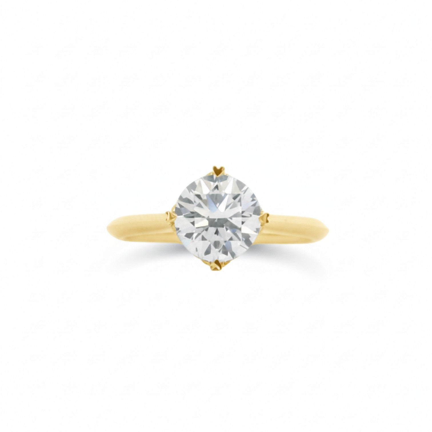 A NSEW solitaire engagement ring with 4 heart prongs in classic 18K yellow gold — Diamond Ateliers.