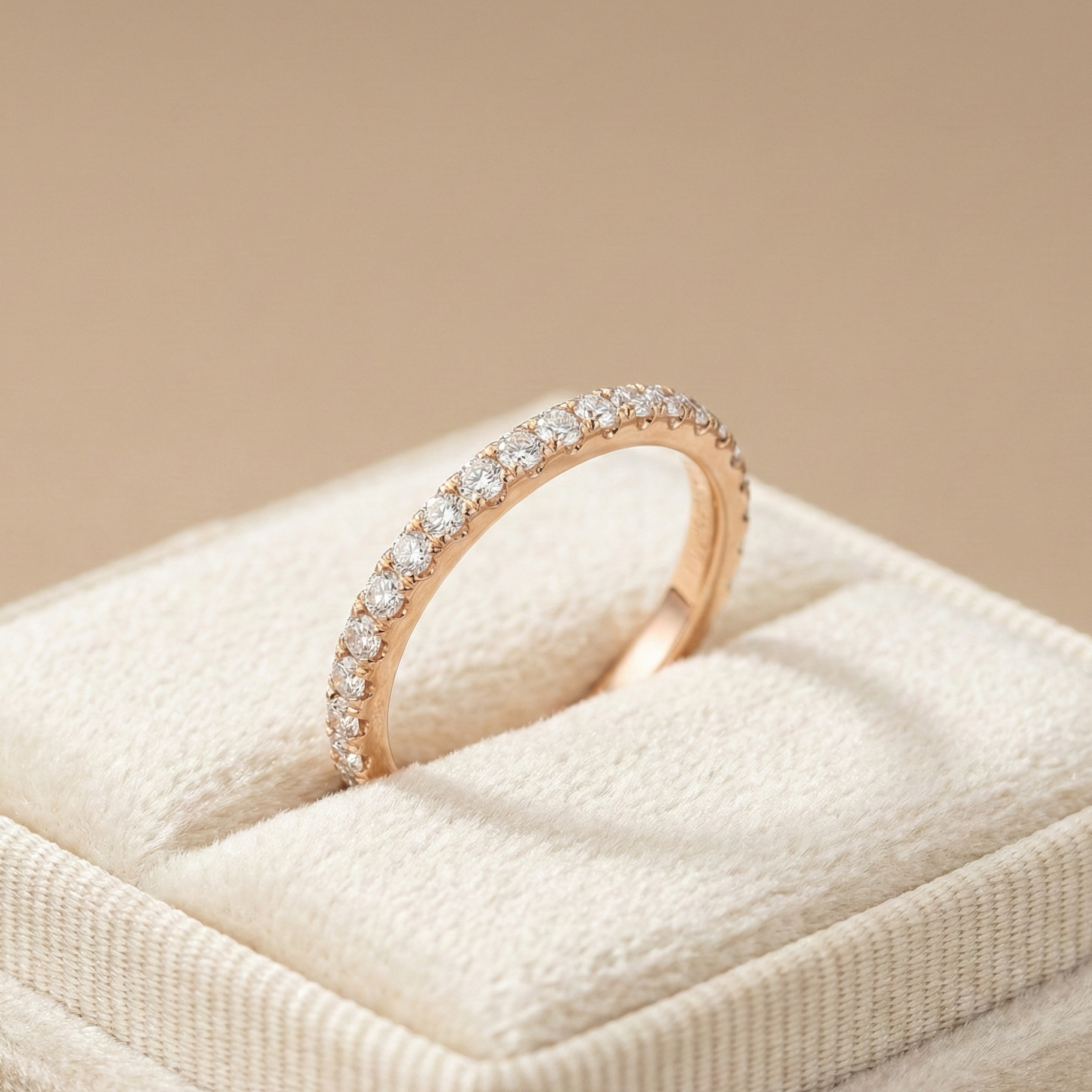 18K rose gold pavé diamond eternity band featuring a full row of round brilliant diamonds, photographed in soft beige studio lighting on a velvet ring box.