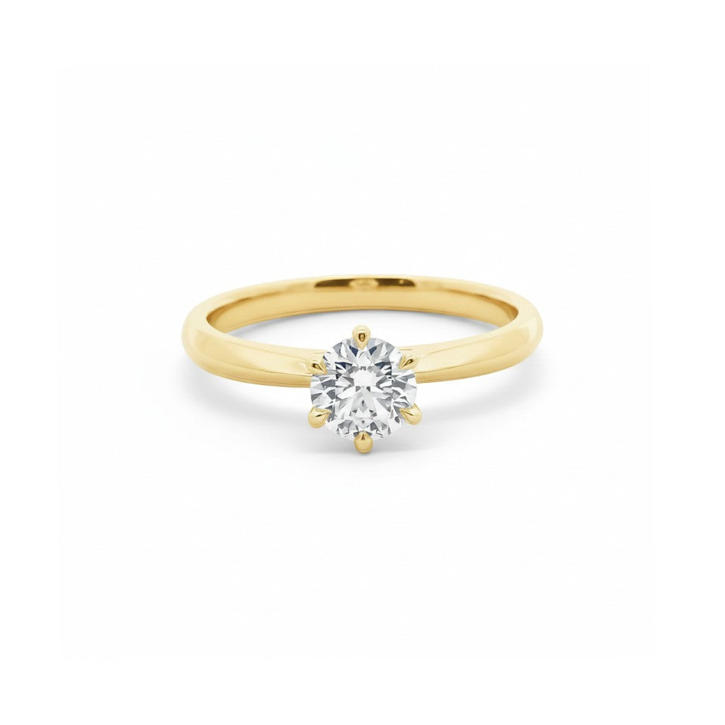 A six-prong round diamond solitaire engagement ring in timeless 18K yellow gold — Diamond Ateliers.