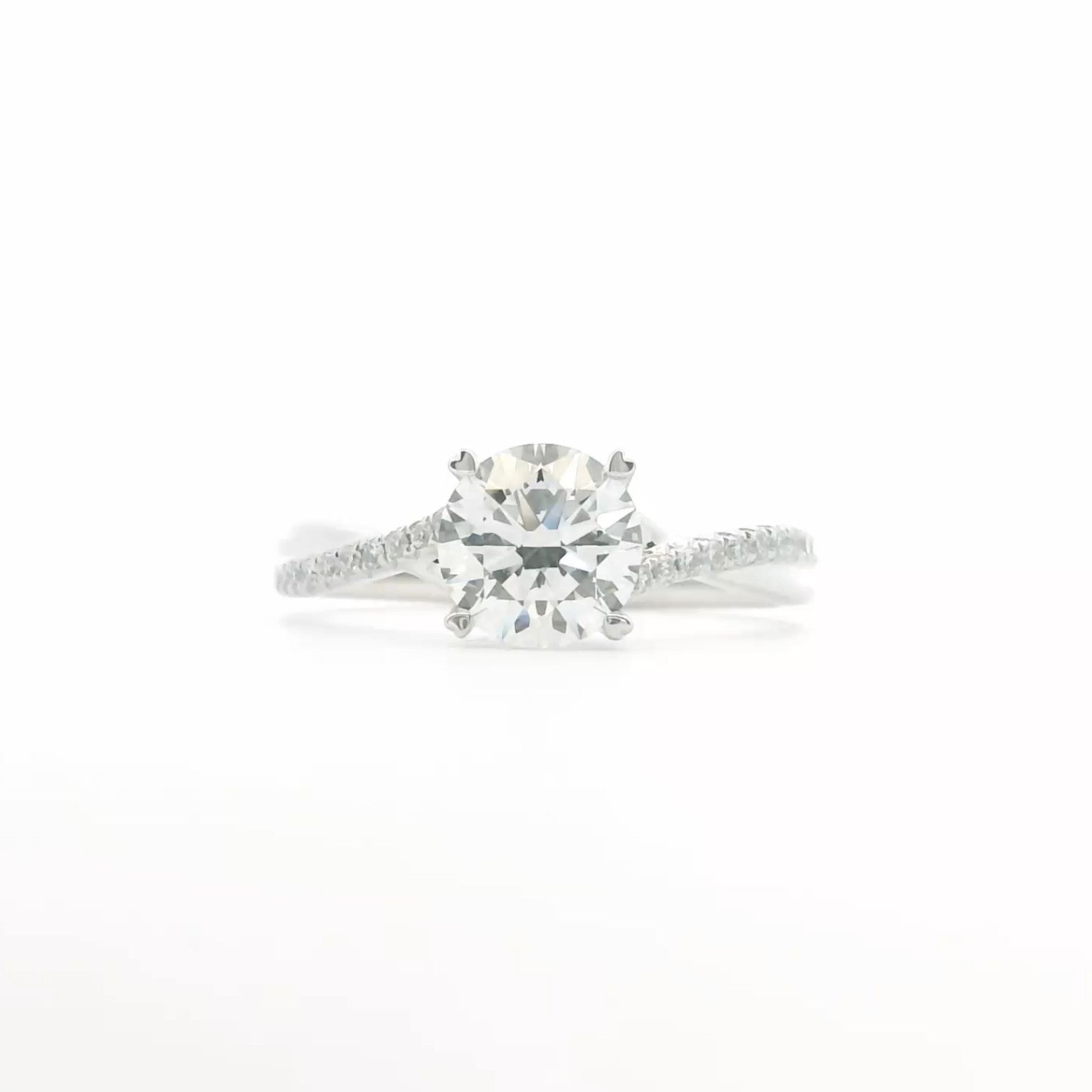 A twisted pavé band engagement ring with a round diamond and 4 claw prongs in 18K white gold — Diamond Ateliers.