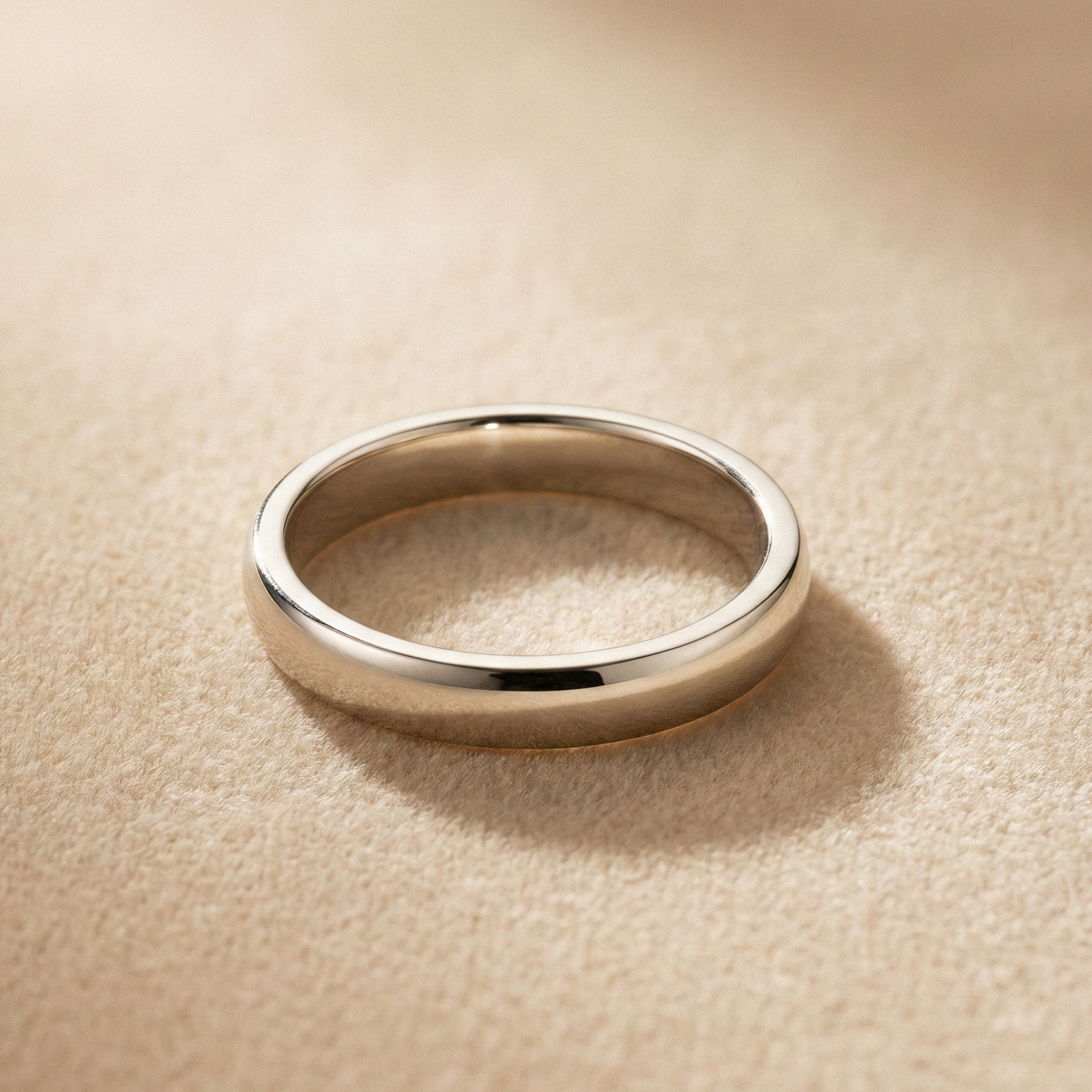 18K white gold wedding band with modern rounded profile on a soft beige background